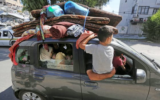 13日、家財道具を車に積み、パレスチナ自治区ガザ北部から南部へ避難する人たち=ロイター